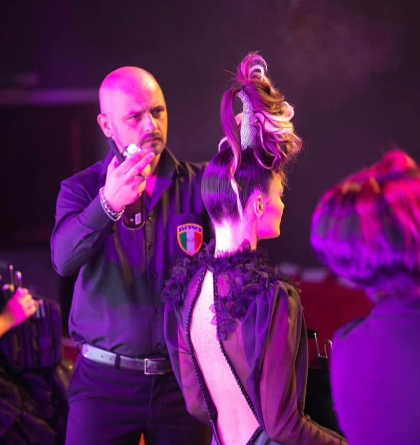 Luca Paparone rifinisce un'acconciatura scultorea durante uno show di acconciatura